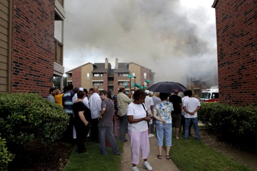 Residents watch as Irving firefighters work to contain a fire at the Eagle Crest Apartments...