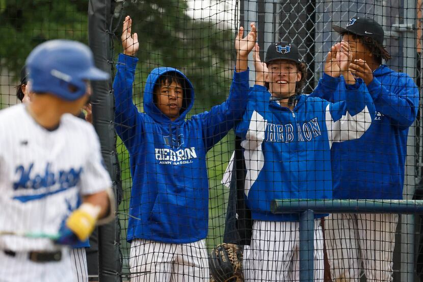 Hebron High players cheers from the dug out during the first inning of a baseball game...