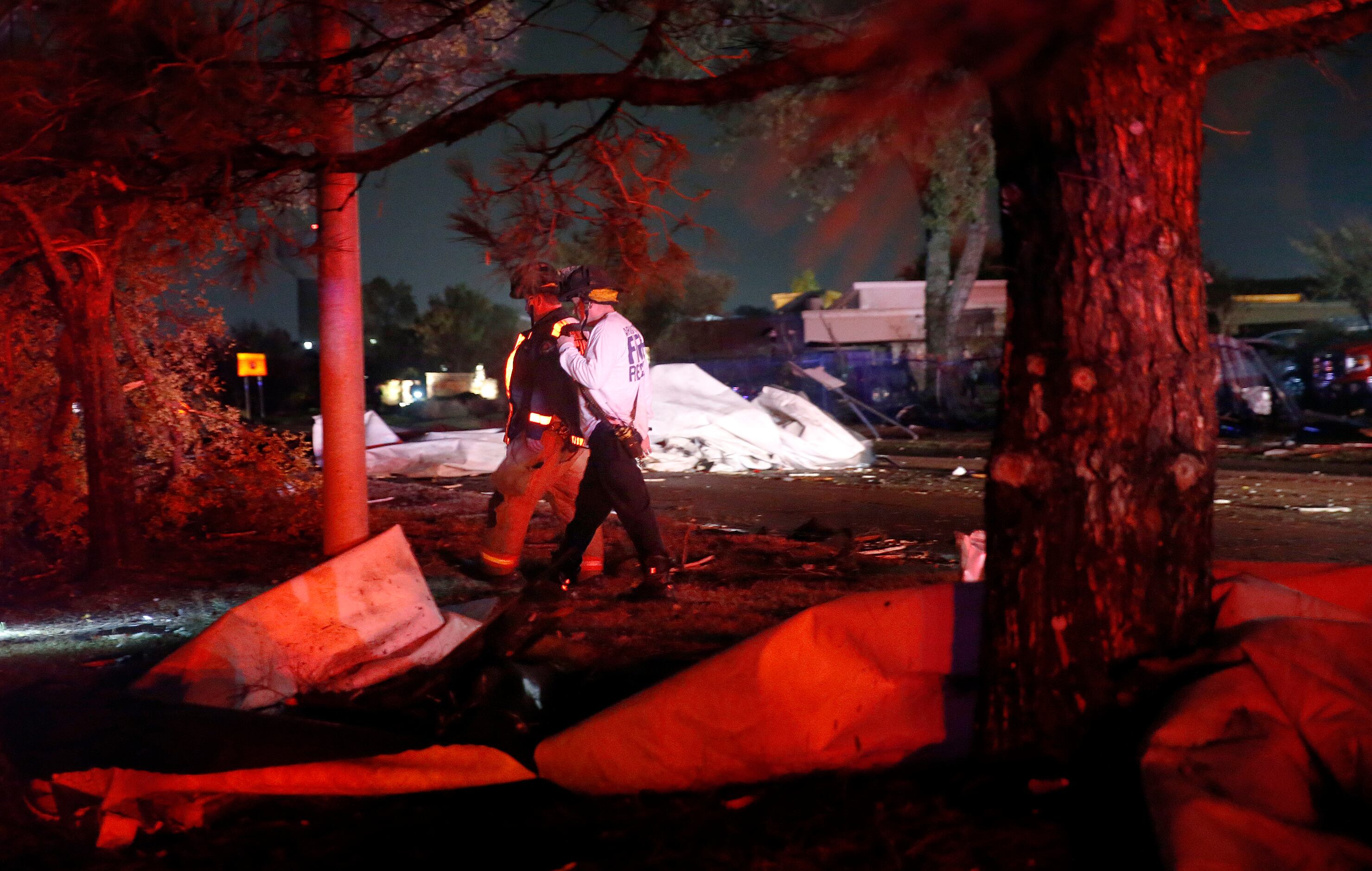A pair of firefighters inspect the damage after the roofs of The Mirage Apartments complex...