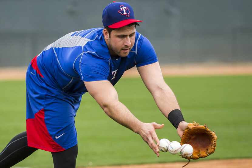 Texas Rangers outfielder Joey Gallo tosses balls into a bag after taking grounders at the...