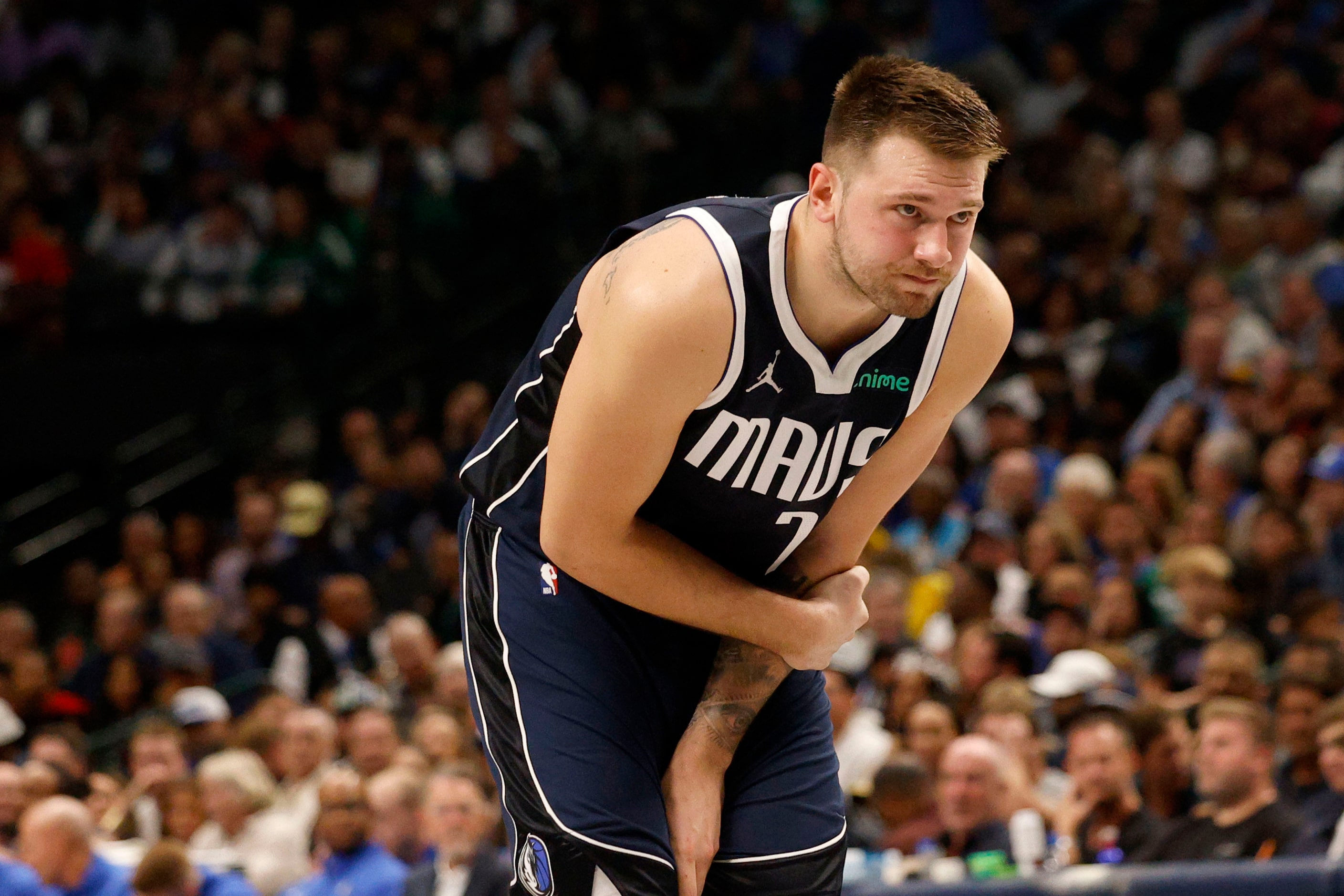 Dallas Mavericks guard Luka Doncic (77) holds his elbow after a fall on the court during the...