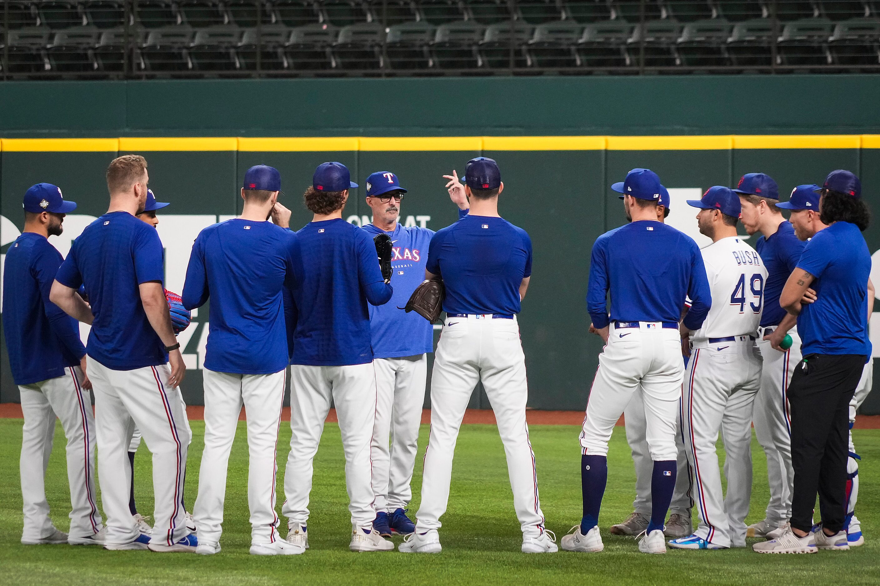 Texas Rangers pitchers gather around pitching coach Mike Maddux during a team workout at...