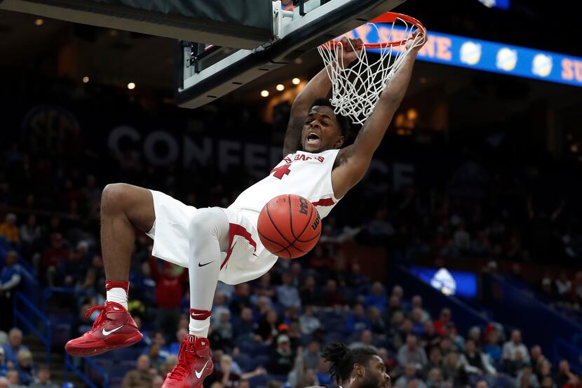 Arkansas' Daryl Macon hangs from the rim after dunking during the first half of an NCAA...