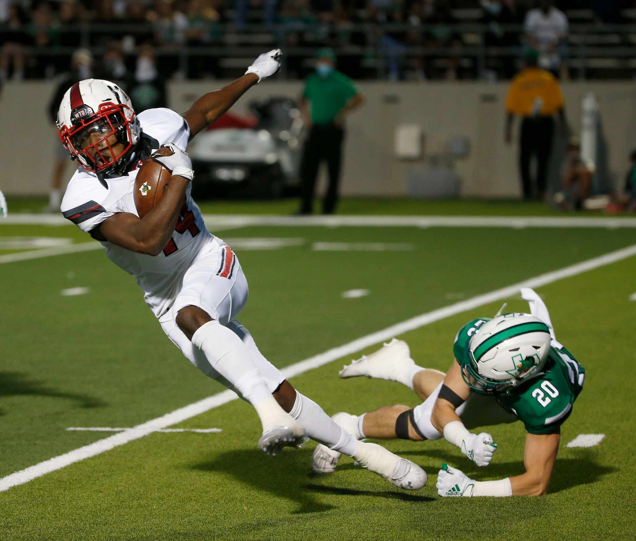 Rockwall Heath’s Burins Lewis (14) is tackled by Southlake Carroll’s Parker Schnieders (20)...