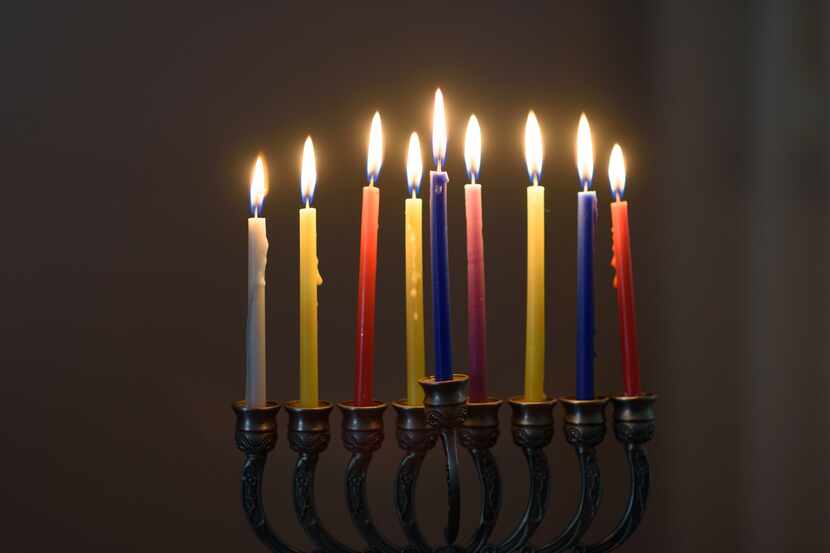 Jewish holiday Hanukkah background with menorah and colorful lighting candles. Rabbi Michael...