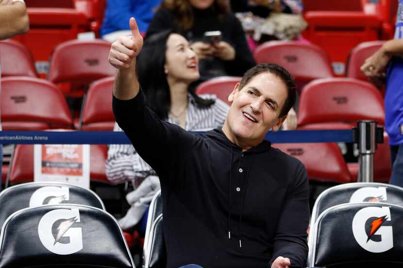 Dallas Mavericks owner Mark Cuban gestures as he sits on the bench before play between the...