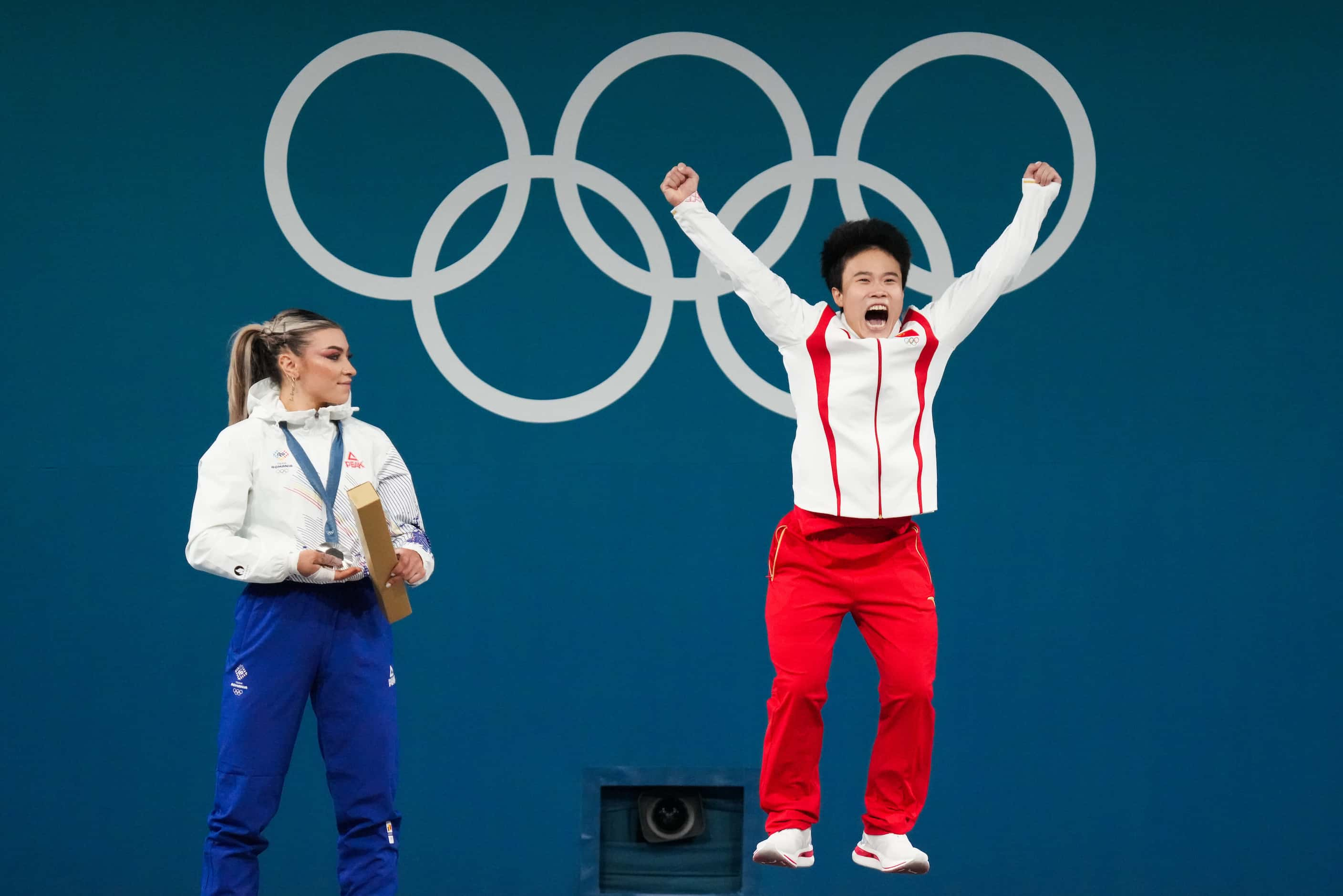 Hou Zhihui of China leaps onto the awards platform after wining gold in women’s 49kg...