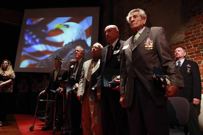 World War ll veteran James Megellas (front right) and other Purple Heart recipients, stand...