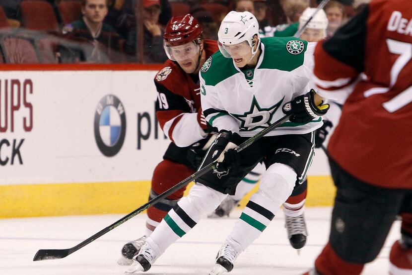 Dallas Stars' John Klingberg (3) advances the puck up ice ahead of Arizona Coyotes' Shane...