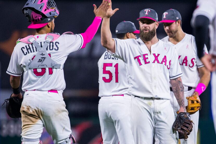 Texas Rangers catcher Robinson Chirinos (61) high fives first baseman Mike Napoli (5) after...