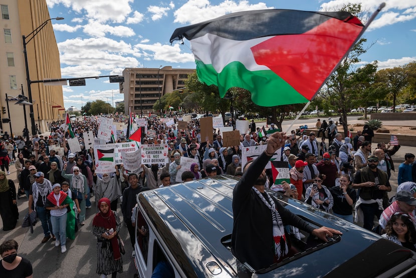 Palestinian Ahmed Abunijmeh, 23, waves a Palestinian flag while riding in a vehicle...