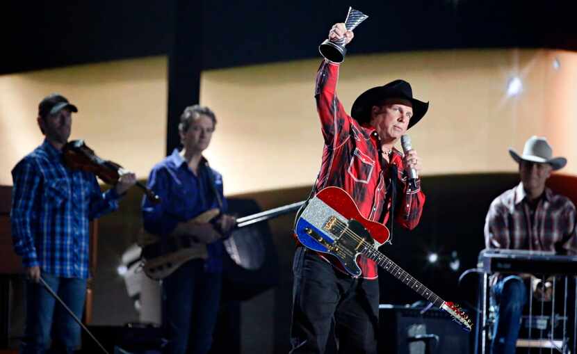 Garth Brooks raises his Milestone Award in the air during the 2015 Academy of Country Music...