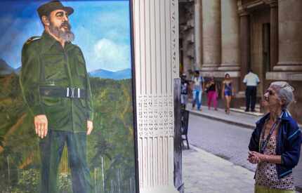 An elderly woman looks at a mural depicting Cuban revolutionary leader Fidel Castro in a...