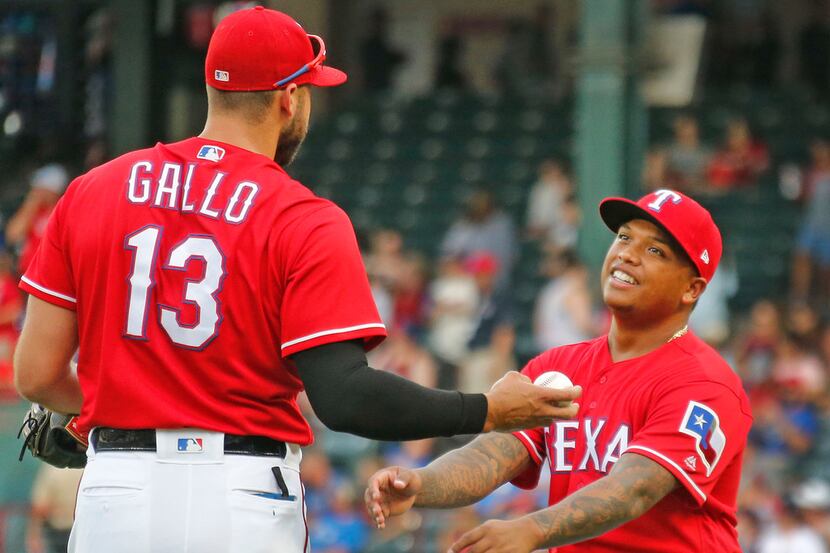 Texas Rangers designated hitter Willie Calhoun (5) talks with Joey Gallo (13) while warming...
