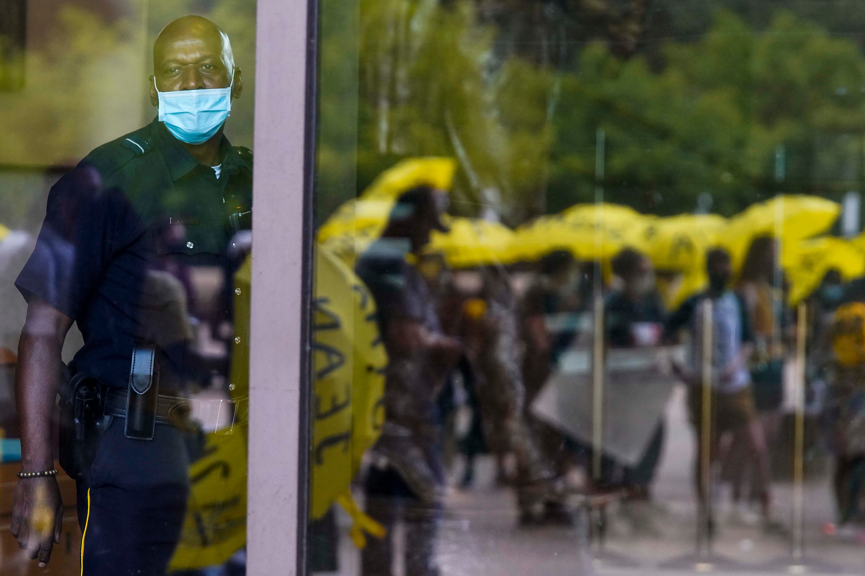 People carrying umbrellas bearing the names of people who have been killed by police or...