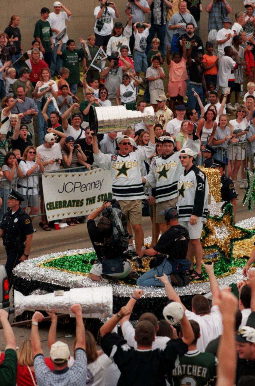Dallas Stars fans celebrate as Stars players hoist the Stanley Cup aboard a float along...