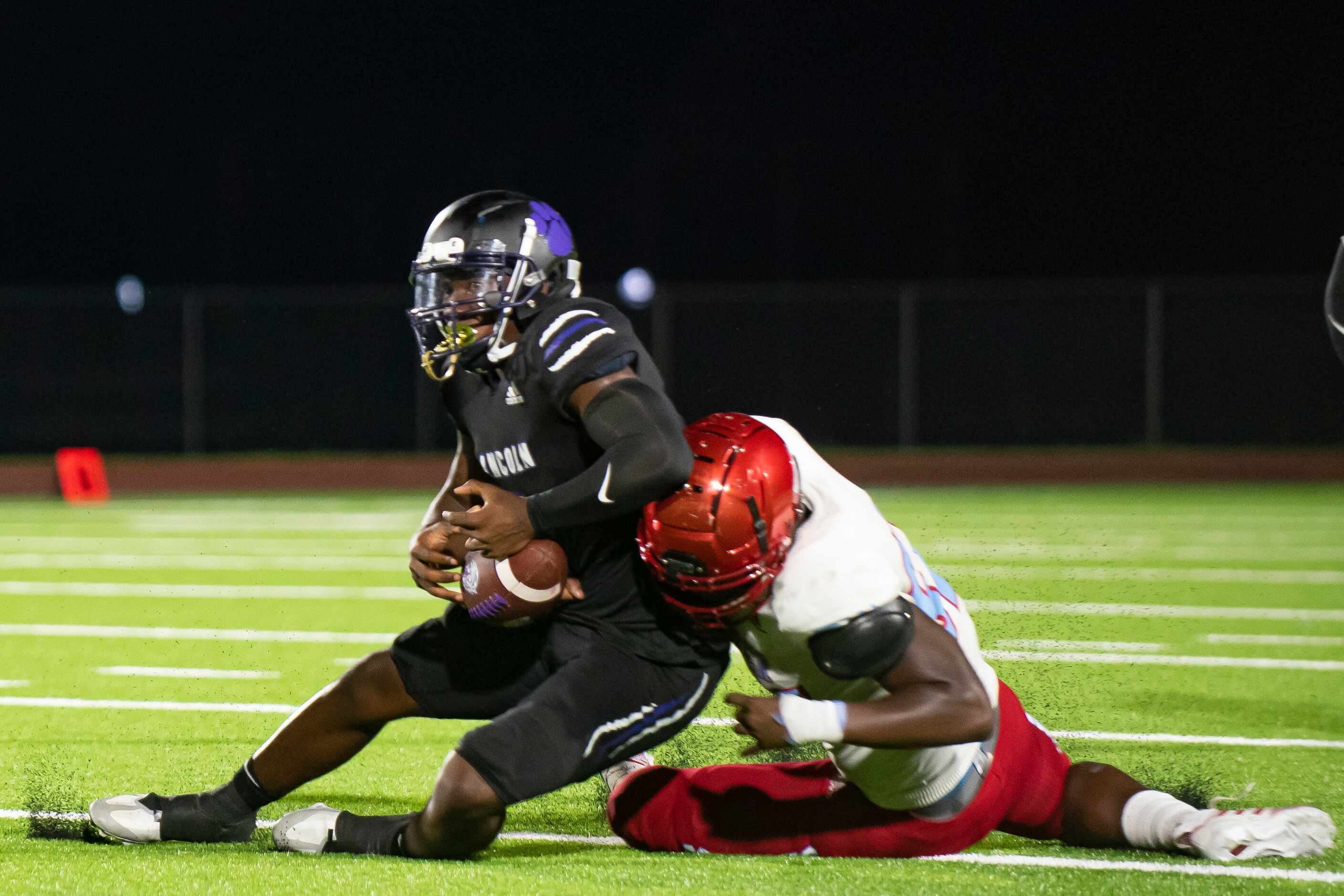 Lincoln senior Jaden Cole (1) is brought down by Carter junior Kristian Johnson (51) in the...