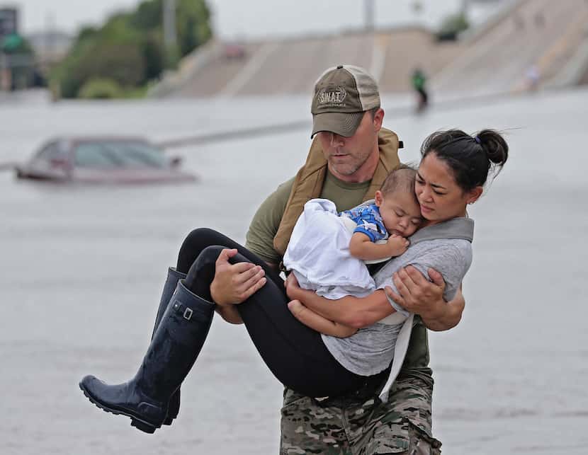 Houston SWAT officer Daryl Hudeck carries Catherine Pham and her son 13-month-old son Aidan...