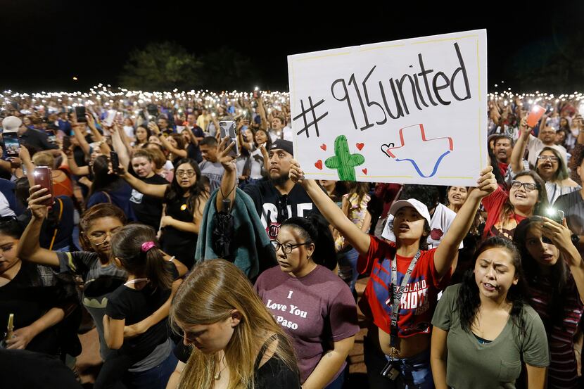 Iliani Ibarra of El Paso holds up a sign as others hold their phones during a vigil at...