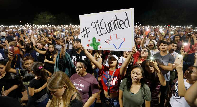 Iliani Ibarra of El Paso holds up a sign as others hold their phones during a vigil at...