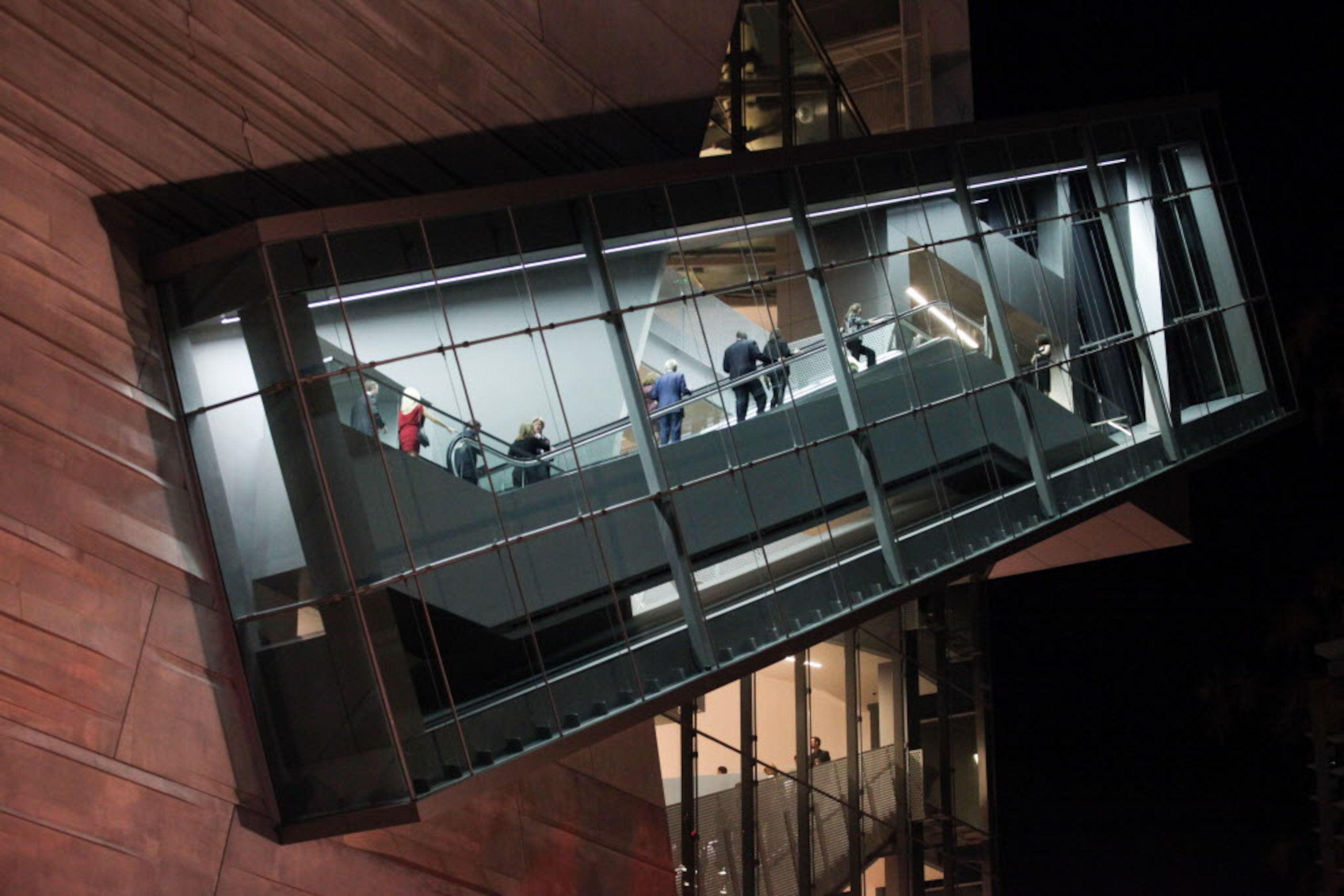 Guests ride the 54-foot continuous-flow escalator contained in a 150-foot glass-enclosed...