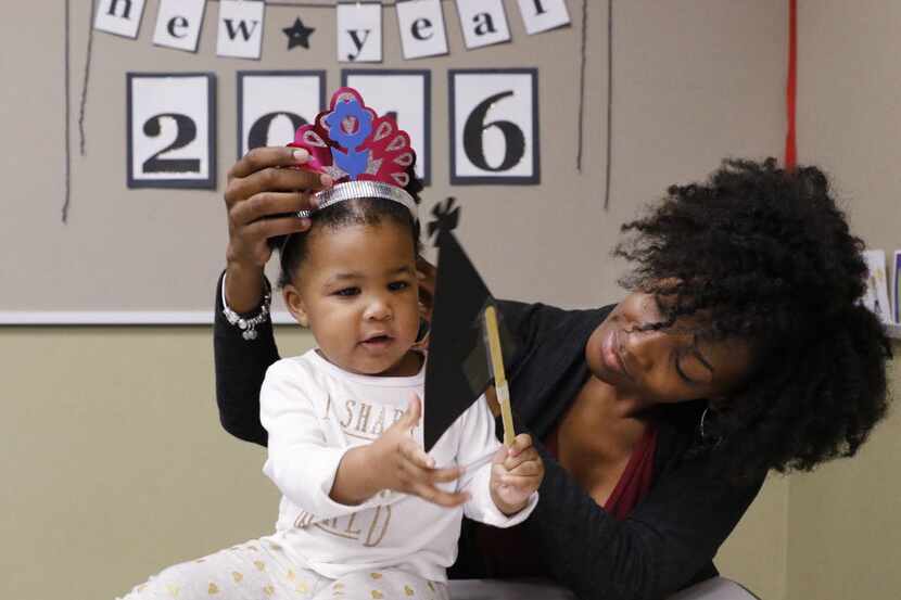 Lachanda Phillips, right, adds a New Year's hat to her daughter, Grace Phillips, 1, during...