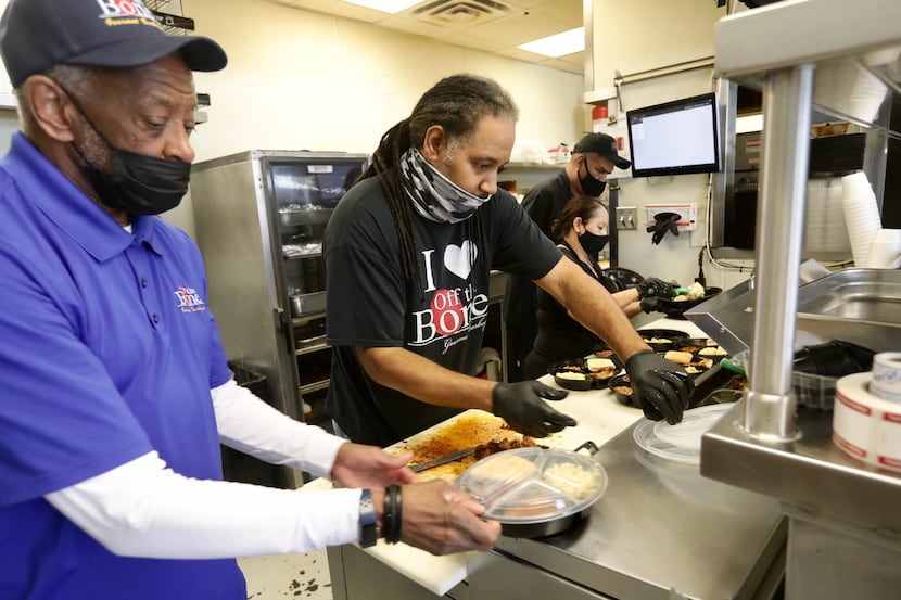 Dwight Harvey, left, and Kelan Williams package up hot food from Off the Bone Barbeque in...
