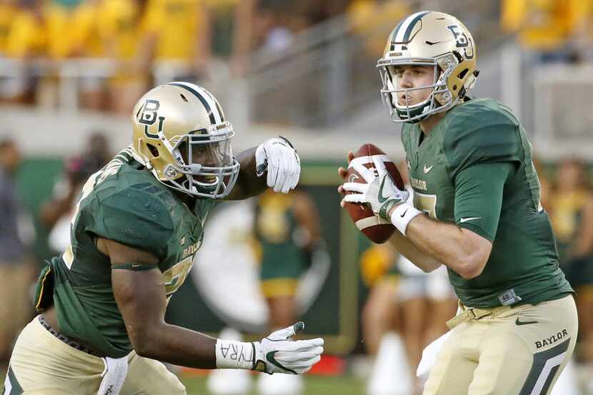 Baylor quarterback Seth Russell (17), right, fakes a handoff to running back Terence...