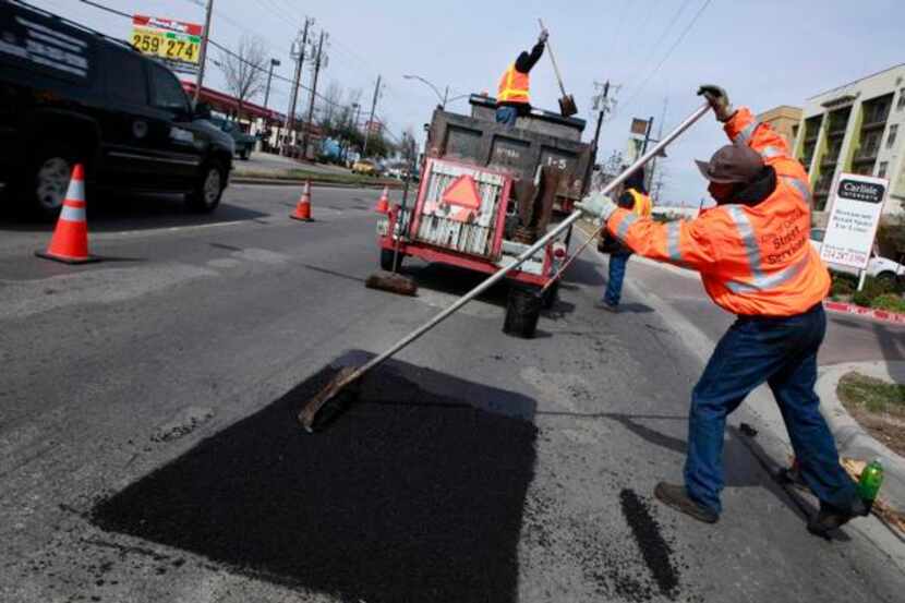 Gary Langley (right) and other Dallas city workers repair potholes on Lemmon Avenue in 2010....