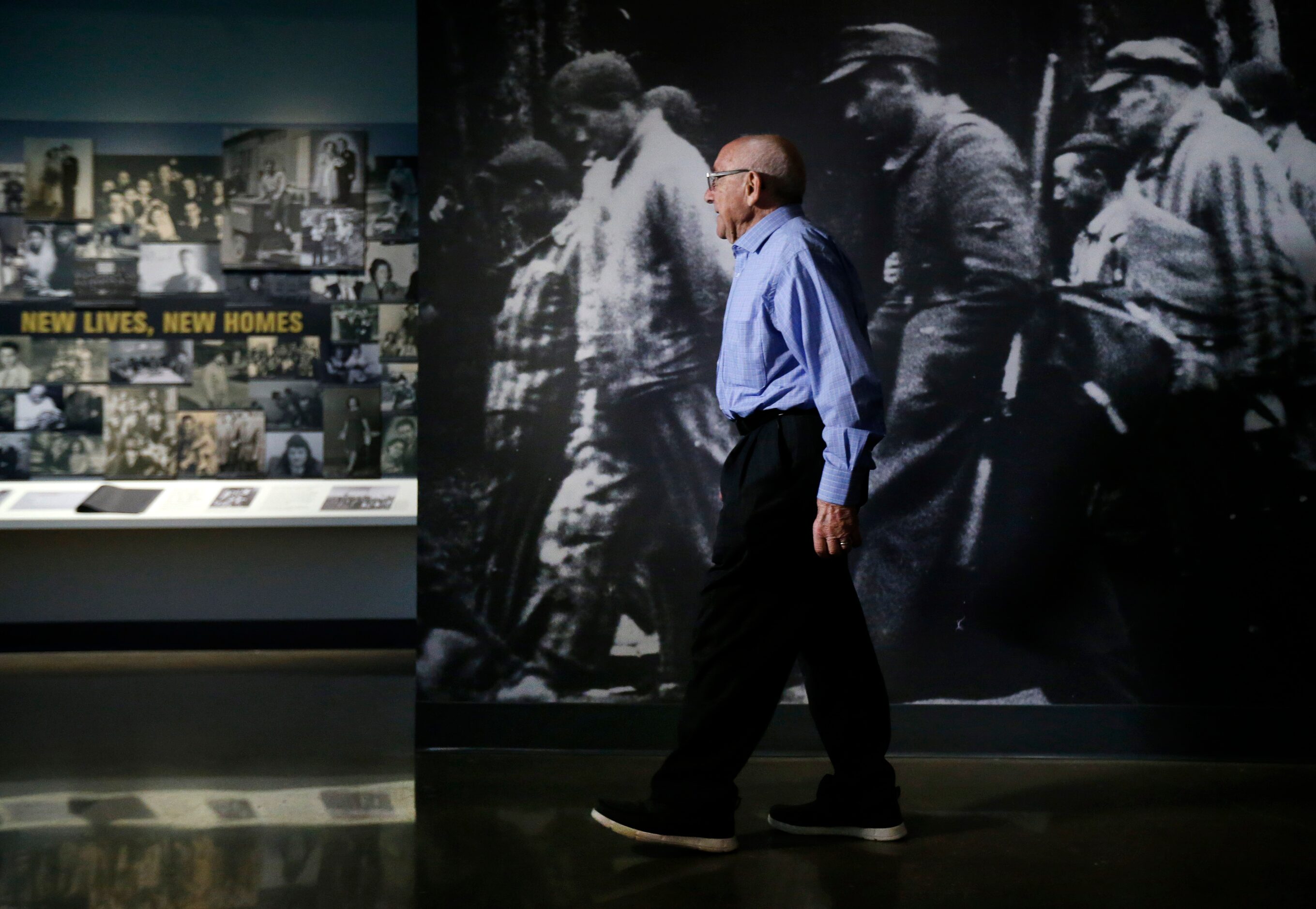 Holocaust survivor Max Glauben walks past a life-sized photo of prisoners on a death march...