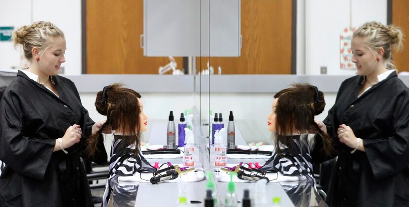 
Macie Vanderburg, a junior from Horn High School, works on the hair of a mannequin in the...