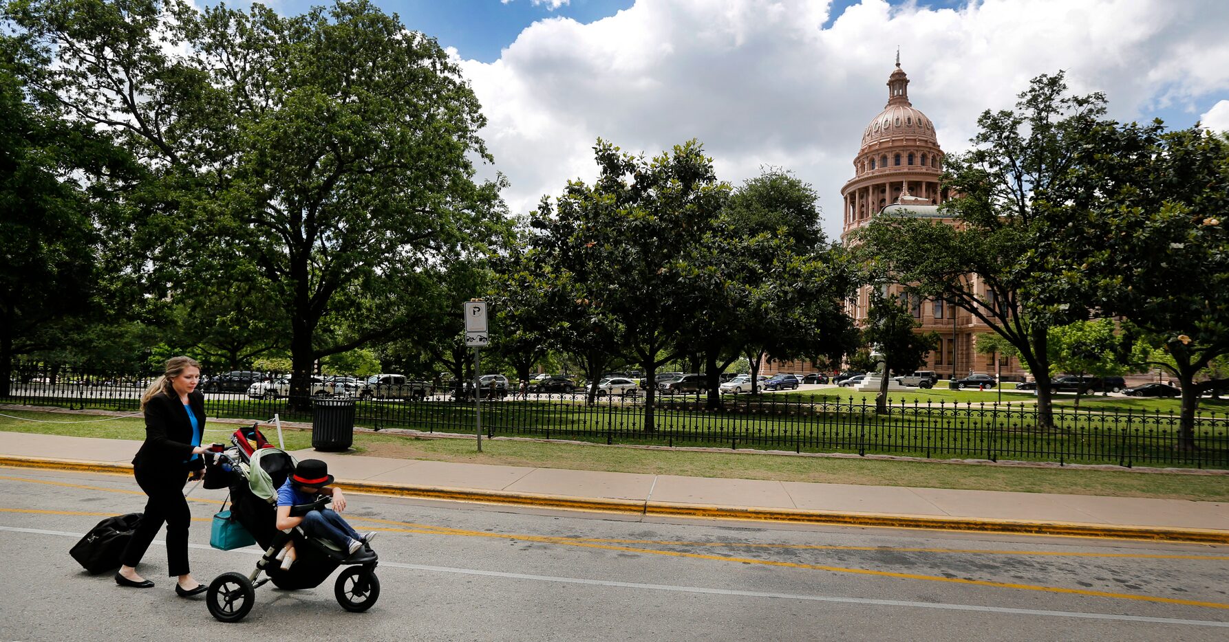 Dragging a rolling case full of documents, Hannah Mehta pushes her 9-year-old son Aiden to...