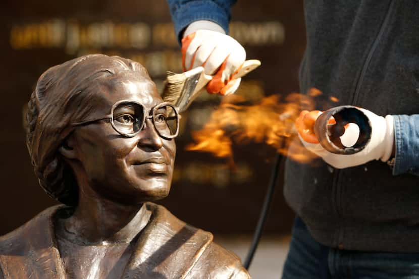 Erik Blome uses a blowtorch in order to warm the brass Rosa Parks statue in order to  apply...