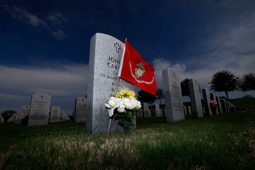 An U.S. Marine Corps flag and flowers sit next to a marker at DFW National Cemetery in...