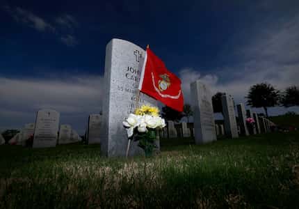 An U.S. Marine Corps flag and flowers sit next to a marker at DFW National Cemetery in...