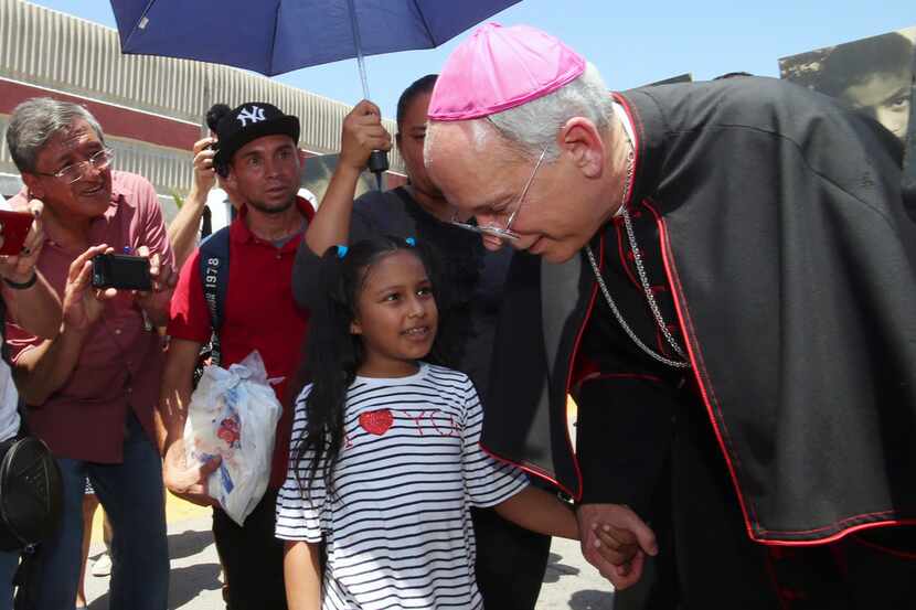 El Paso Catholic Bishop Mark J. Seitz talked with Celsia Palma, 9, of Honduras as they...