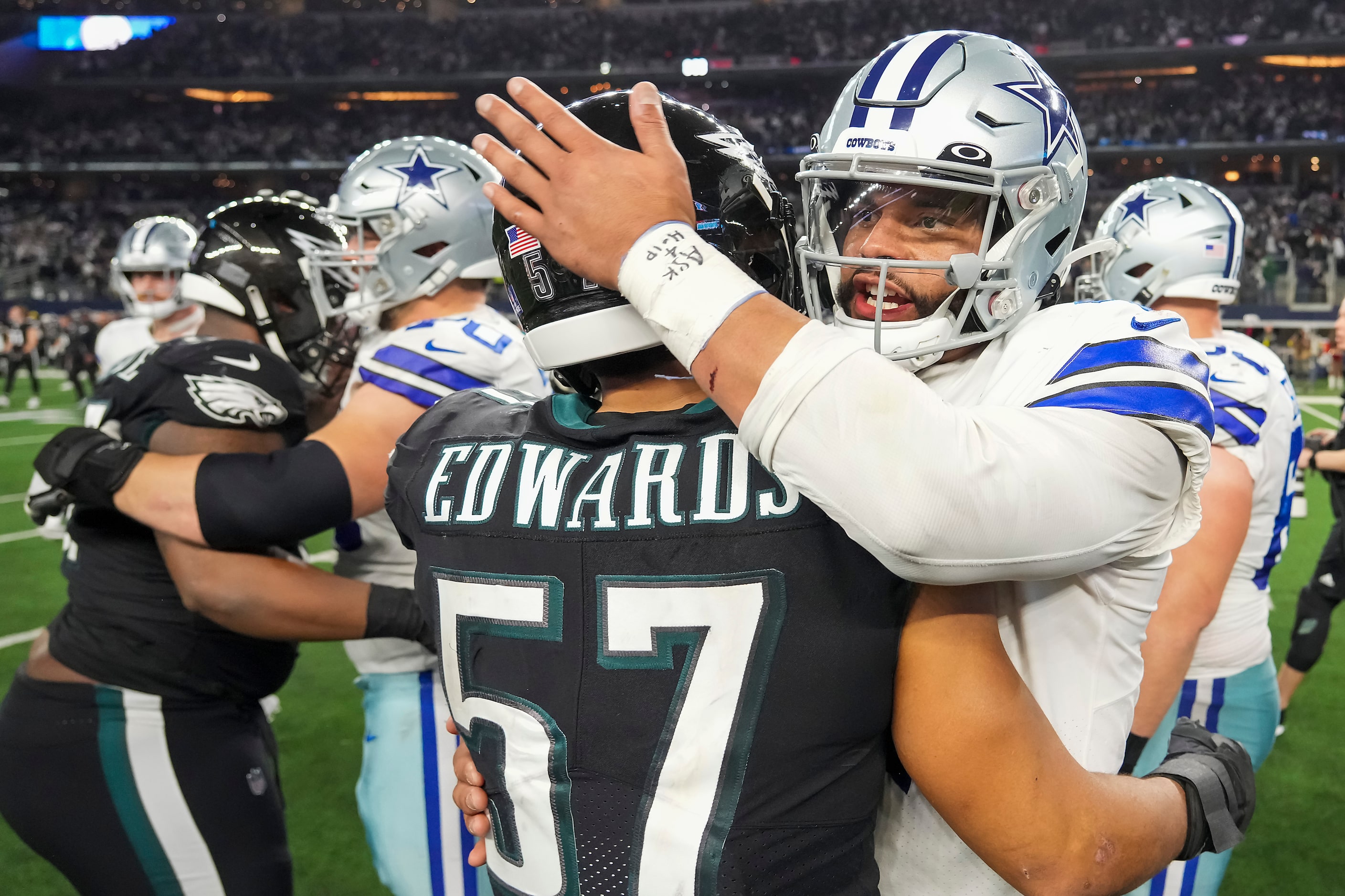 Dallas Cowboys quarterback Dak Prescott (4) hugs Philadelphia Eagles linebacker T.J. Edwards...