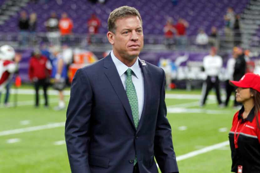 Former Dallas Cowboys quarterback Troy Aikman walks on the field before an NFL football game...