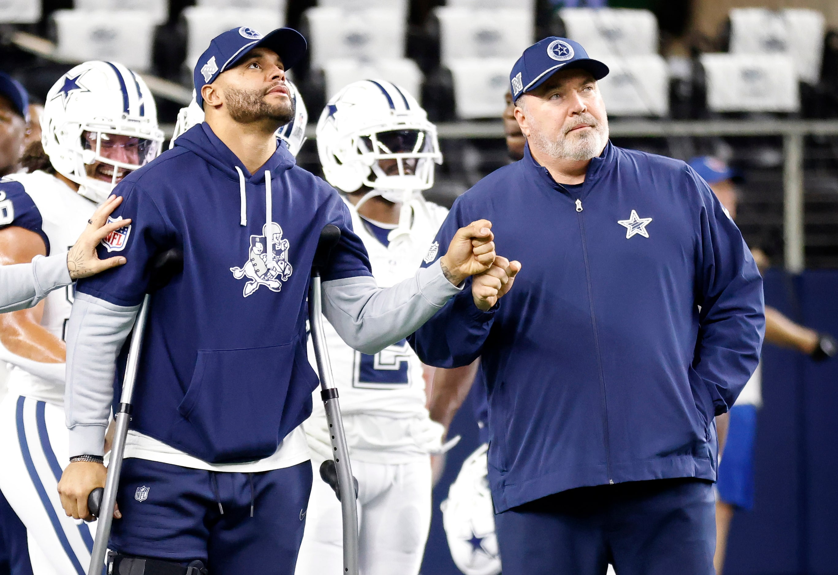 Injured Dallas Cowboys quarterback Dak Prescott (left) fist bumps head coach Mike McCarthy...