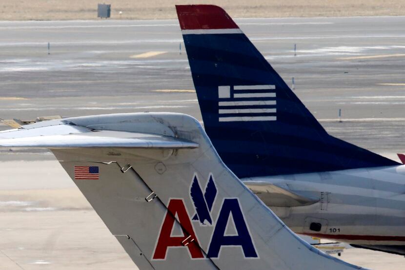 American Airlines and US Airways jets prepare for flight at a gate at the Philadelphia...