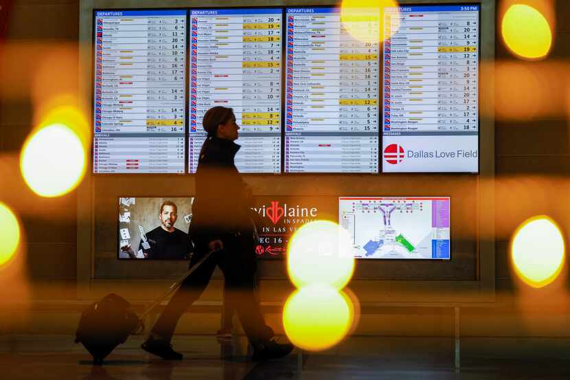 A woman walks past a flight status board at Dallas Love Field airport in Dallas on Dec. 22.