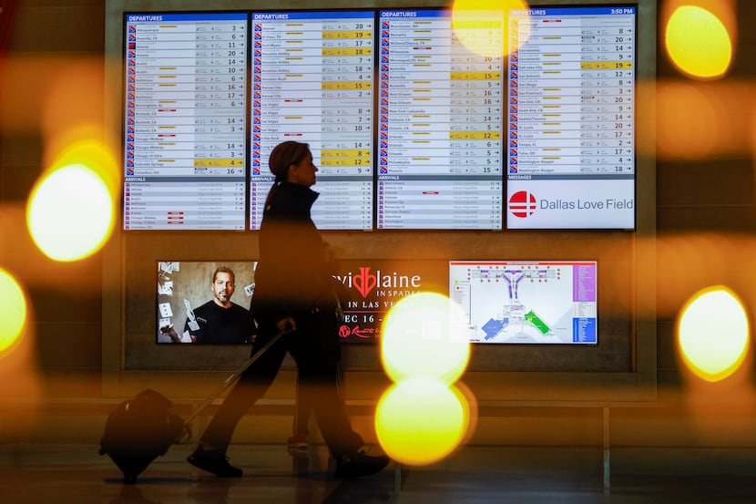 A woman walks past a flight status board at Dallas Love Field airport in Dallas on Dec. 22.