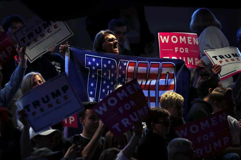 Women shout and hold up Donald Trump banners and signs during a campaign rally for...