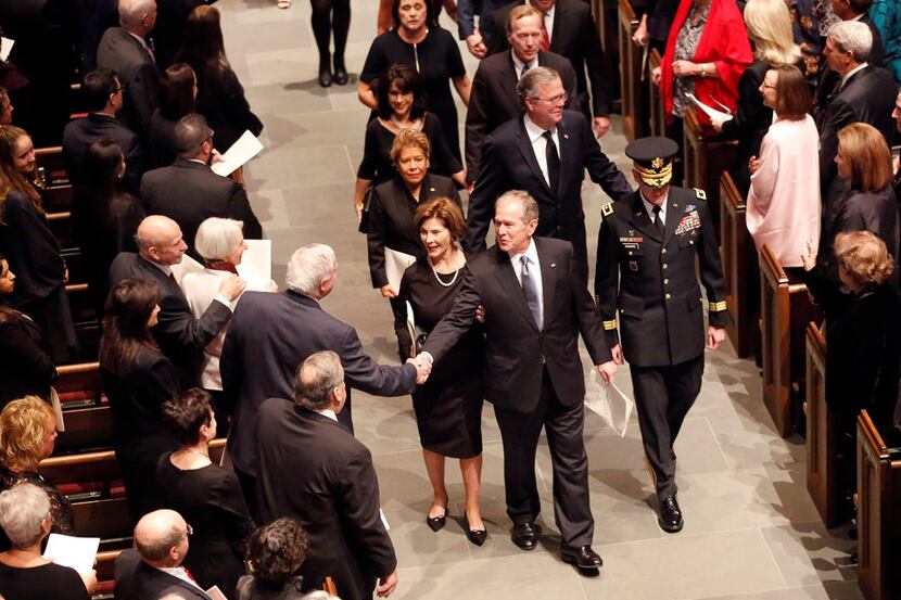 Former President George W. Bush and first lady Laura Bush are greeted by well-wishers during...