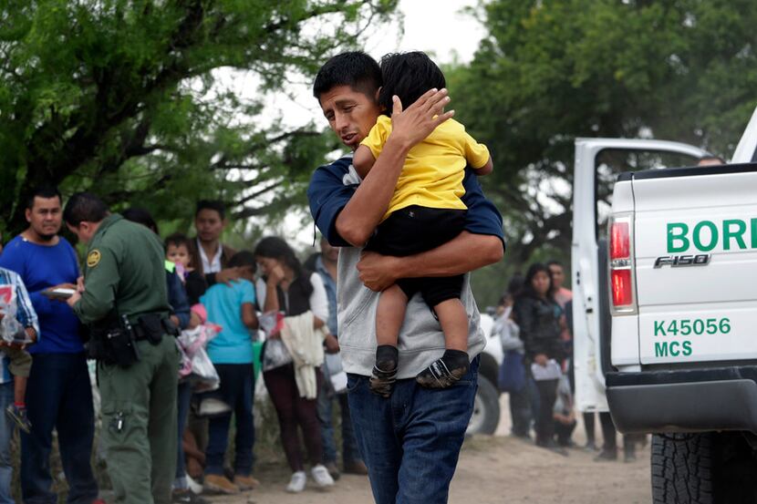 Jose Fermin Gonzalez Cruz holds his son, William Josue Gonzales Garcia, 2, as they wait with...