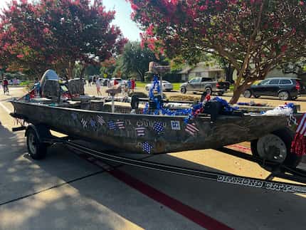 Boat outfitted in Independence Day decorations being pulled by a trailer.