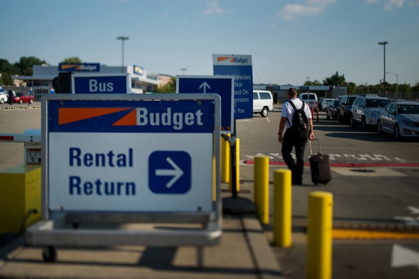 A traveler walks towards vehicles at the Avis Budget Group Inc. location for LaGuardia...