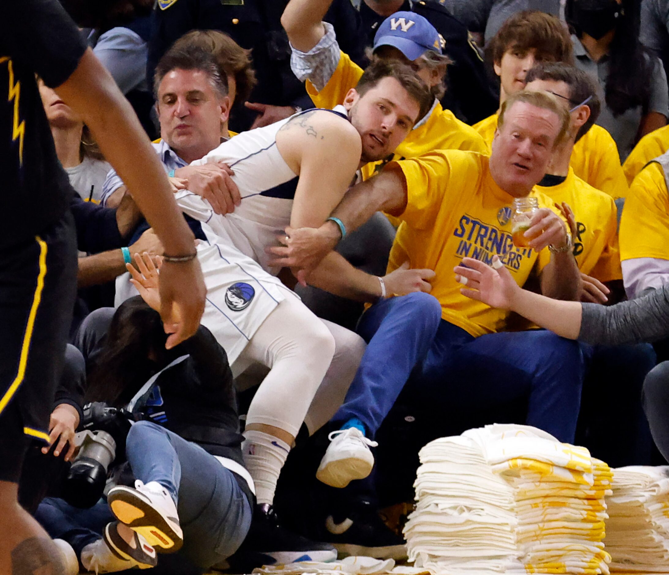 Dallas Mavericks guard Luka Doncic (77) ends up in the lap of Golden State Warriors fans...