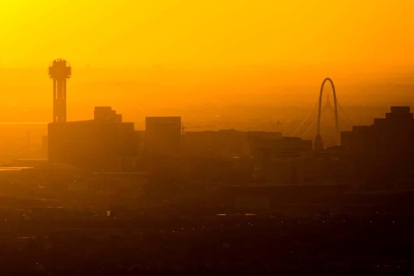 Sun setting behind the Downtown Dallas skyline and the Margaret Hunt Hill Bridge on...