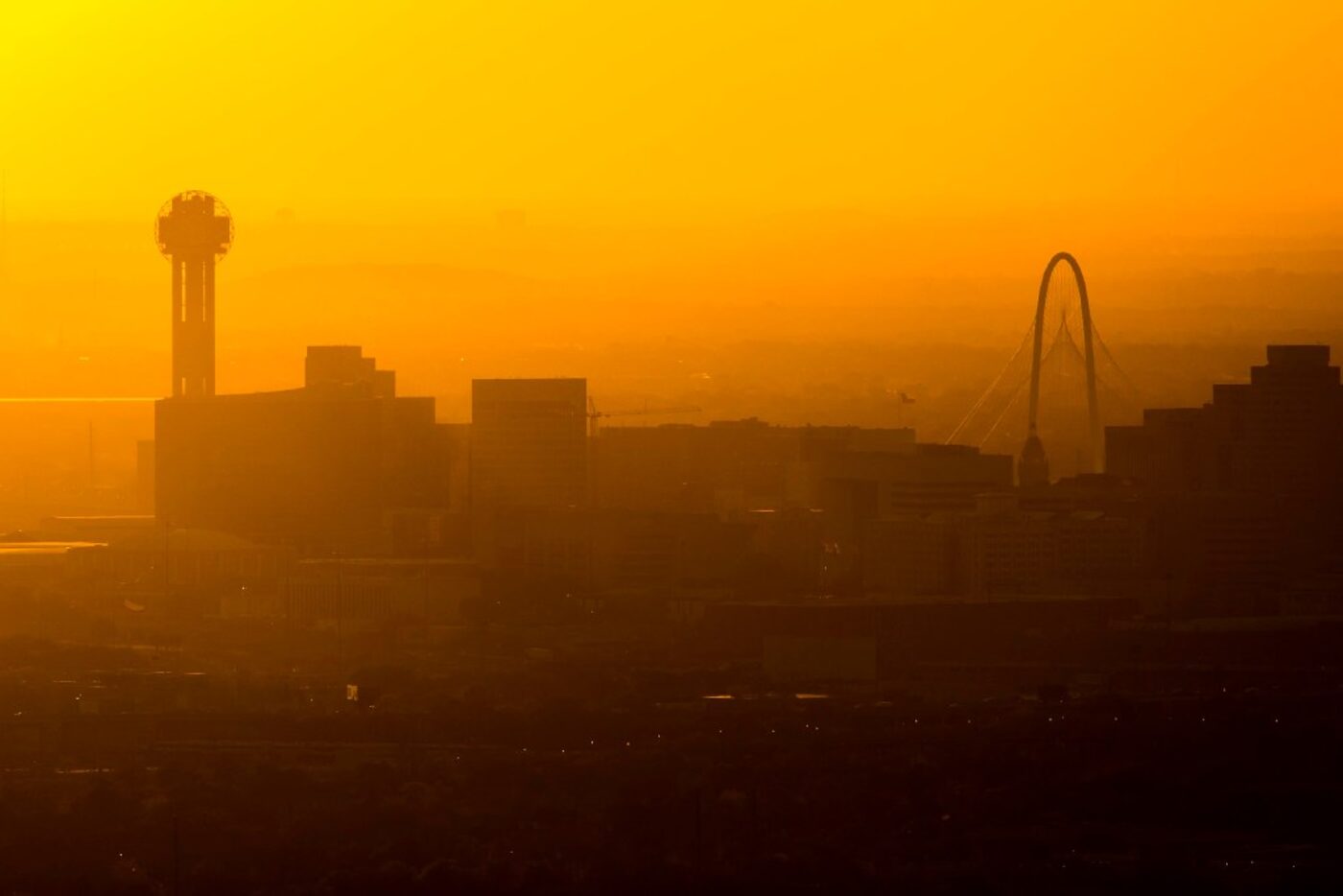 Sun setting behind the Downtown Dallas skyline and the Margaret Hunt Hill Bridge on...